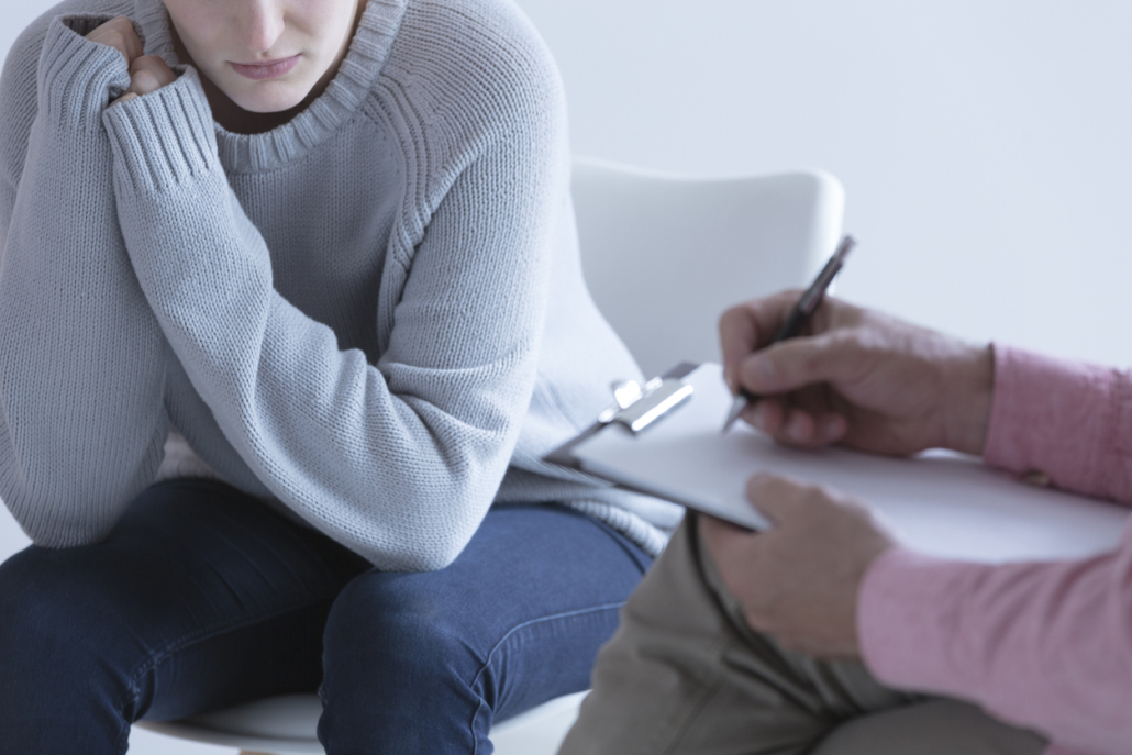 Young female talking to an adult who is writing on paper on a clipboard